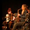 Christine Abdelnour. Une femme saxophoniste en train de jouer avec une accordéoniste en arrière plan.